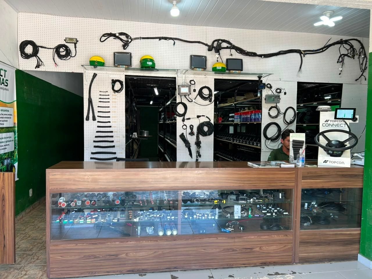 Interior da loja Connect Máquinas — balcão e painel com chicotes e monitores